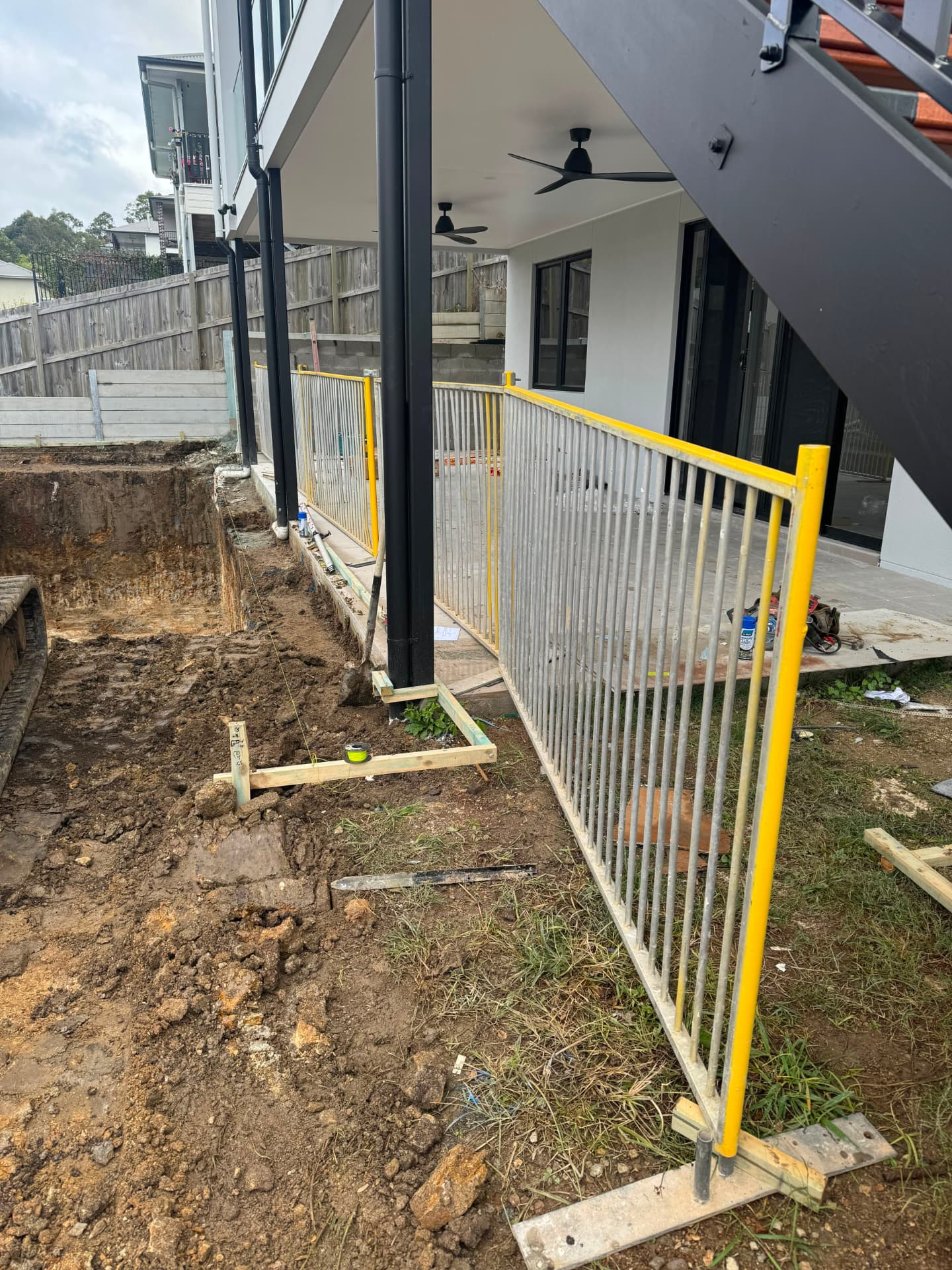 Temporary pool fencing beside a new pool dig under an alfresco
