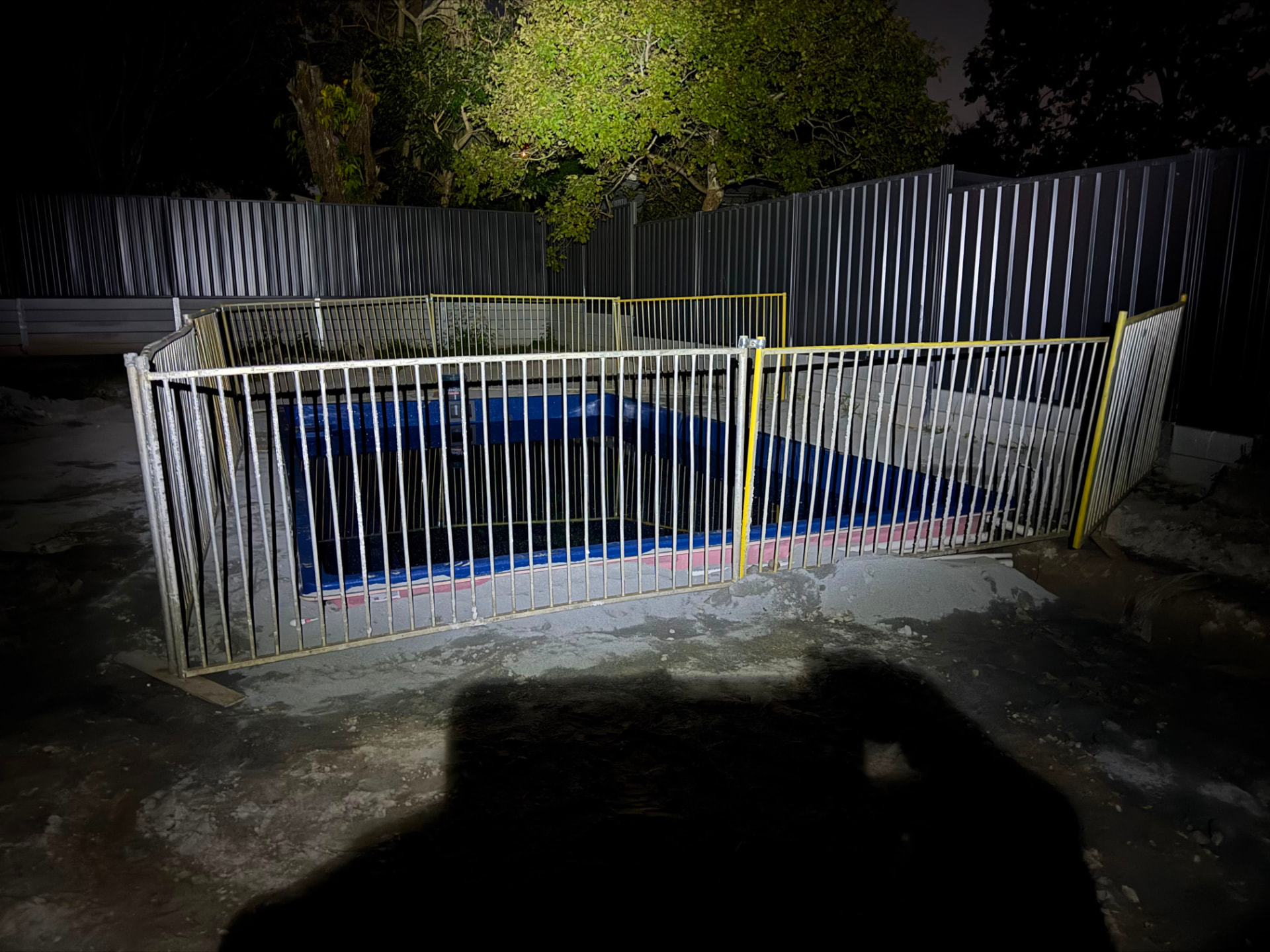 Temporary pool fencing around a plunge pool at night