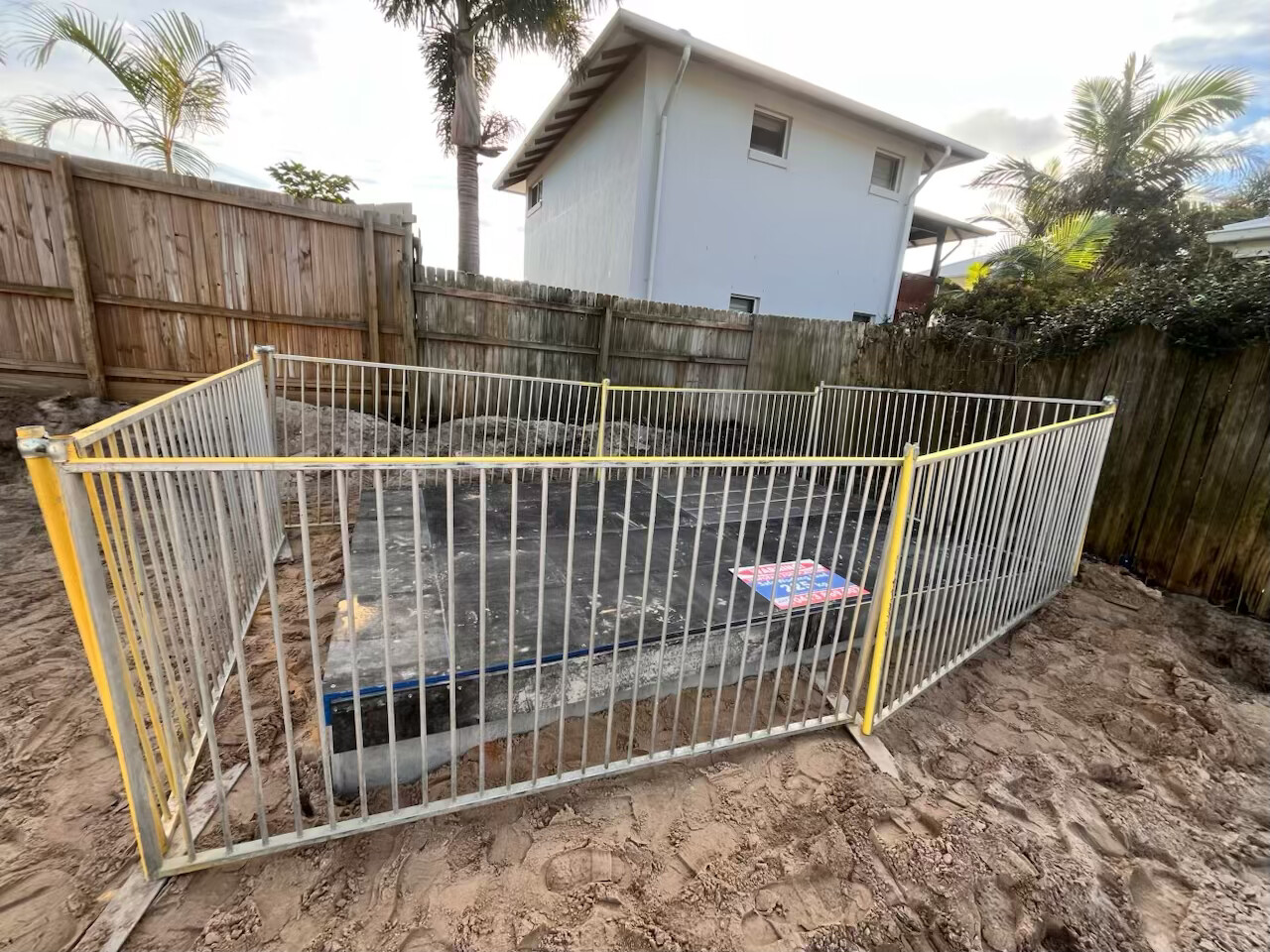 Temporary pool fence panels installed along a timber boundary fence
